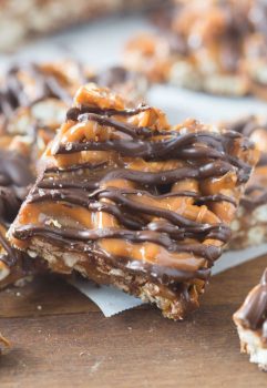 A close up of a square pretzel bar with a pretzel crust and chocolate and caramel drizzled on top.
