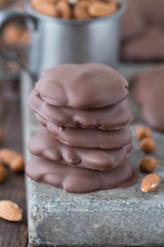 A stack of five Sticky Paws next to almonds on a board.